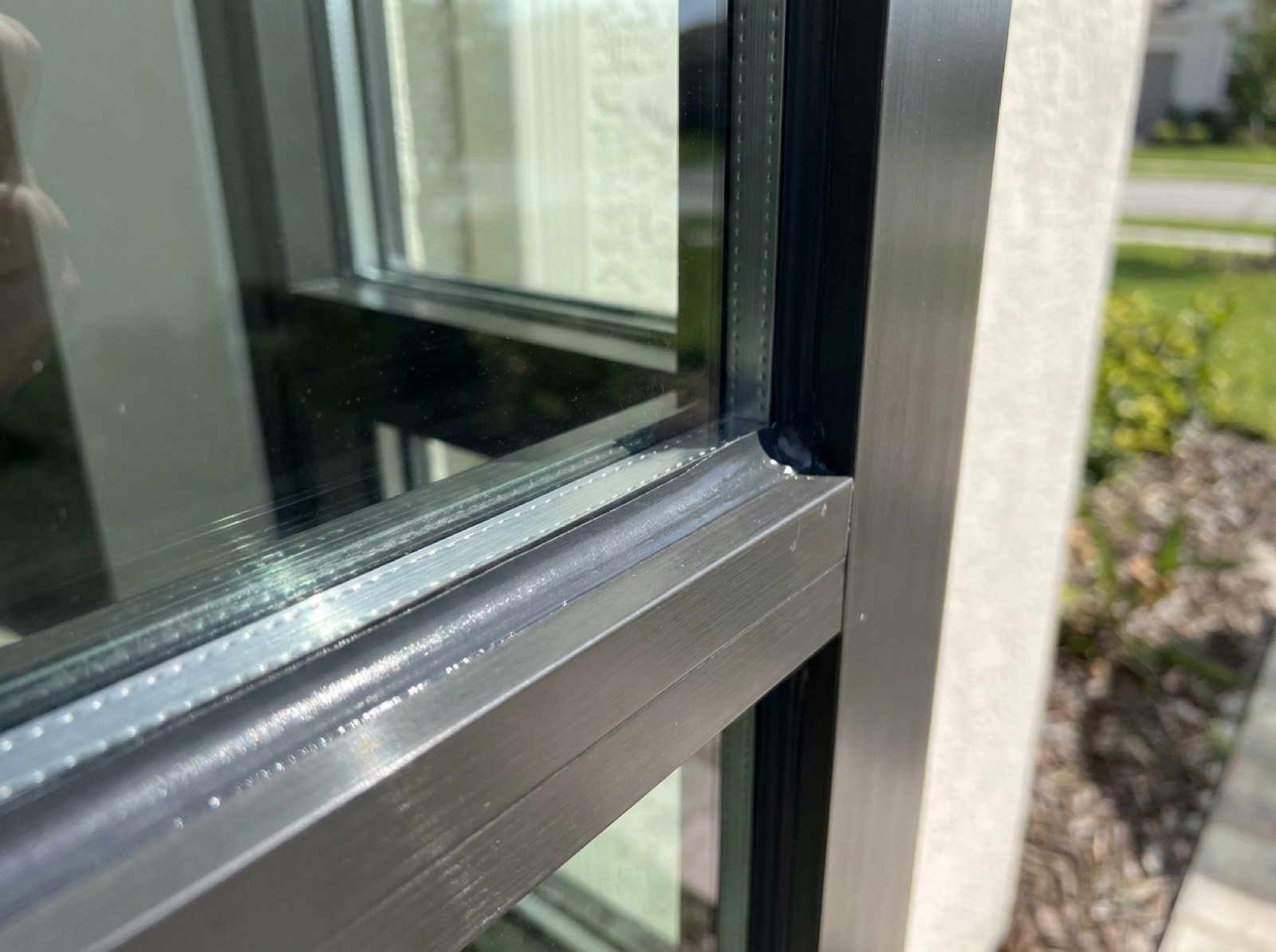 Close-up of a laminated impact window installation with sealed aluminum frame